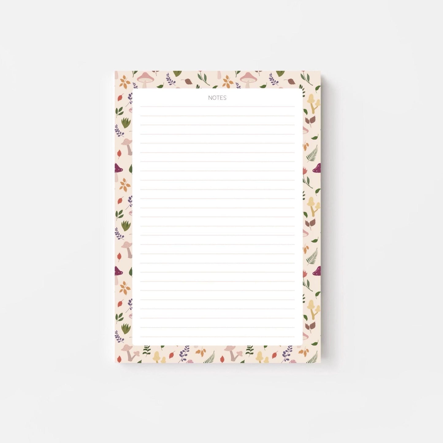 A lined notepad on a white background, with a beige border patterned with autumn leaves and mushrooms