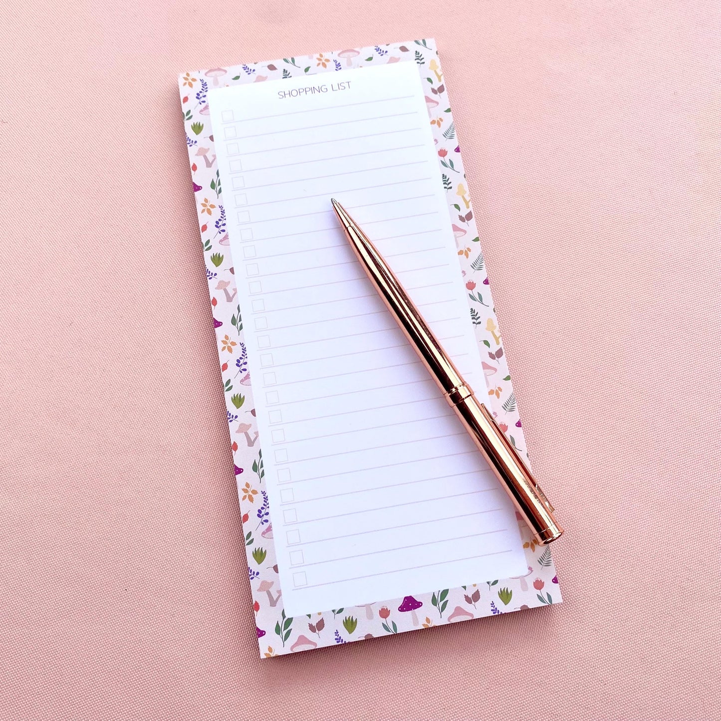 Autumn foliage-patterned shopping list notepad on a pink background