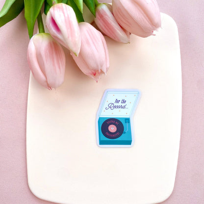 Pink tulips on a white surface with a blue record player sticker.