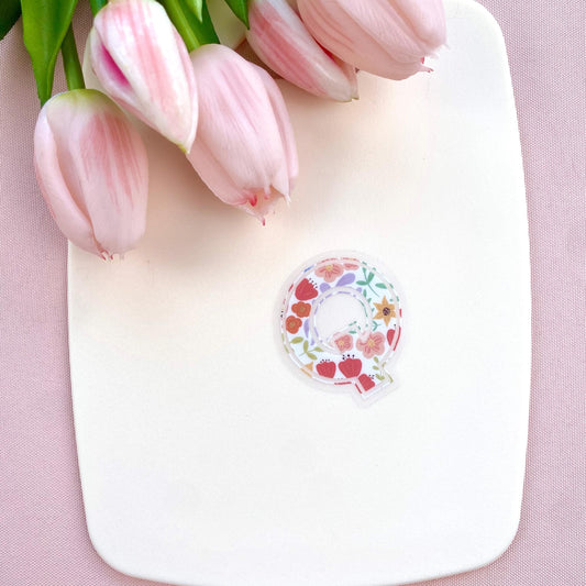 Decorative letter 'Q' sticker with floral patterns on a light background with pink tulips.