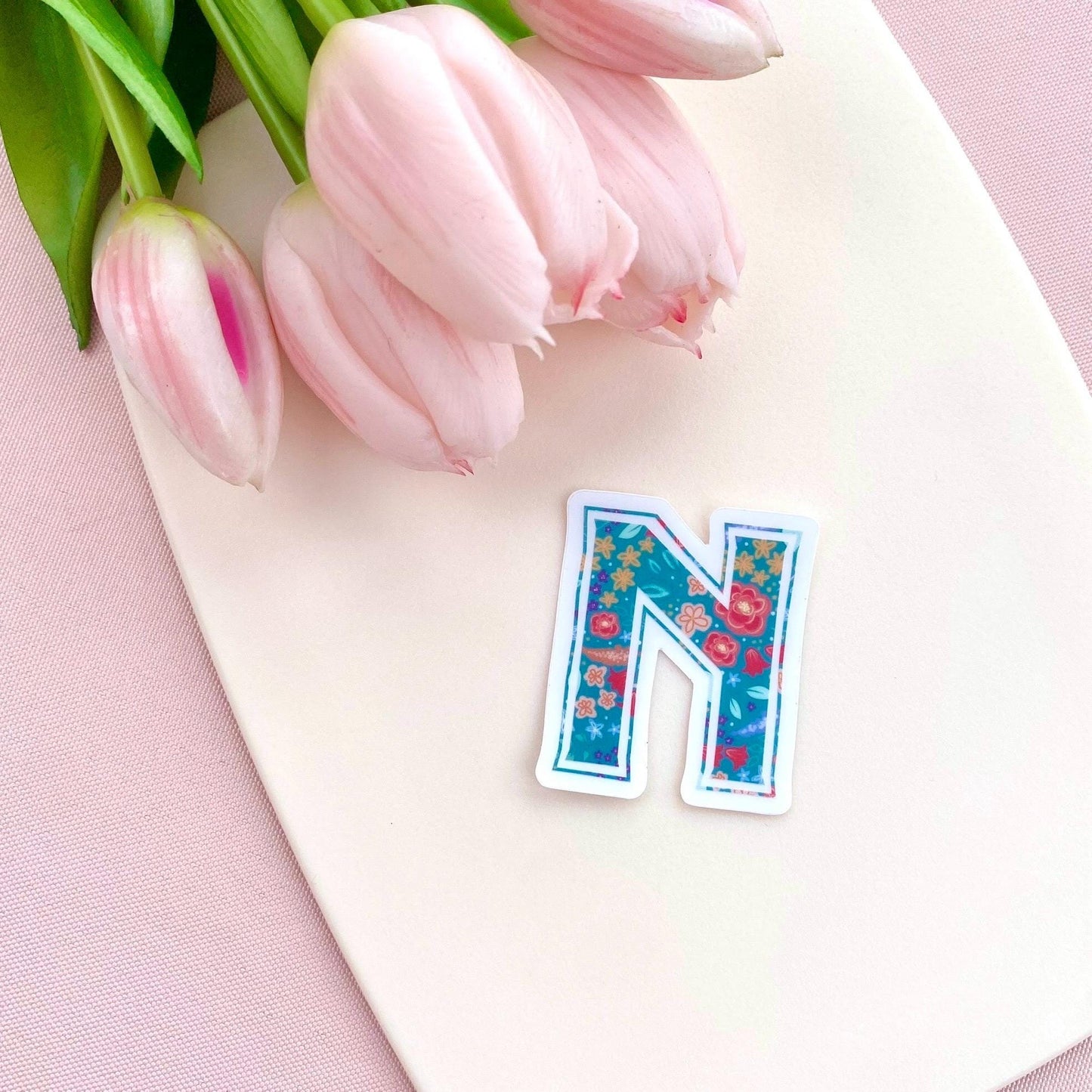 Floral letter 'N' sticker on a cream background with pink tulips