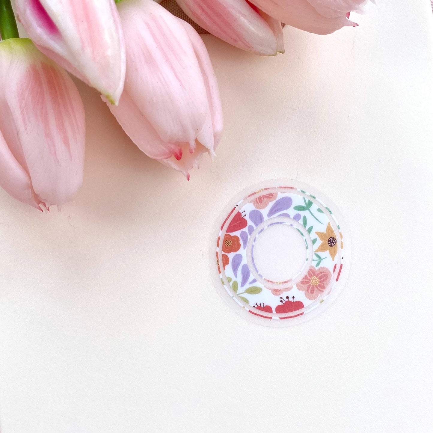 Decorative letter 'O' sticker with floral patterns on a light background with pink tulips.