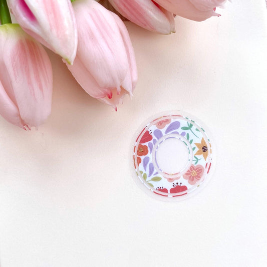 Decorative letter 'O' sticker with floral patterns on a light background with pink tulips.