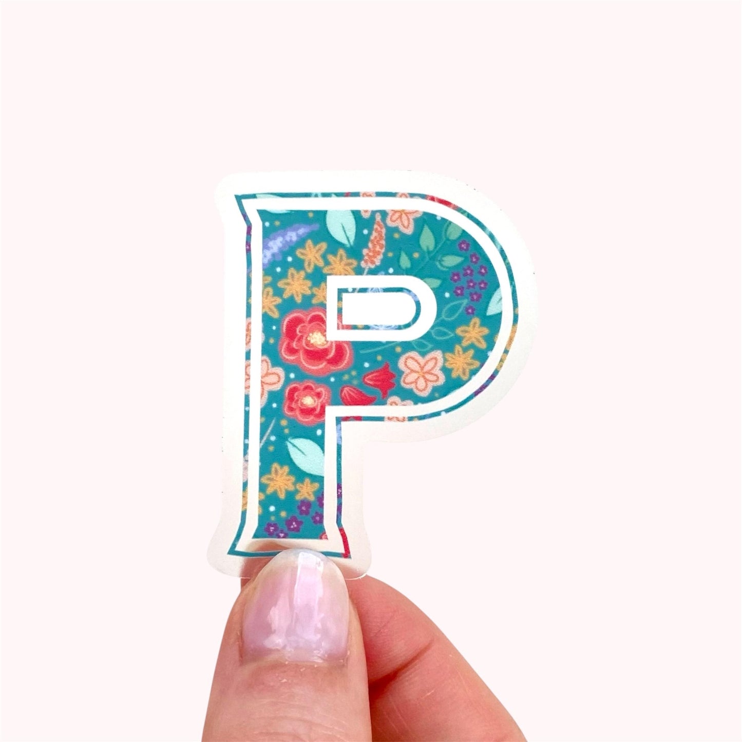 Decorative letter 'P' sticker with floral pattern held by hand against a white background