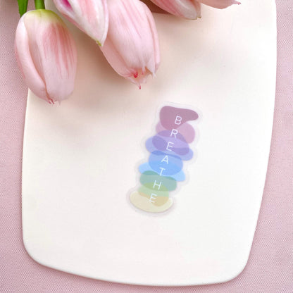 Colorful 'BREATHE' decal on a white surface with pink tulips in the background