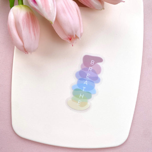 Colorful 'BREATHE' decal on a white surface with pink tulips in the background