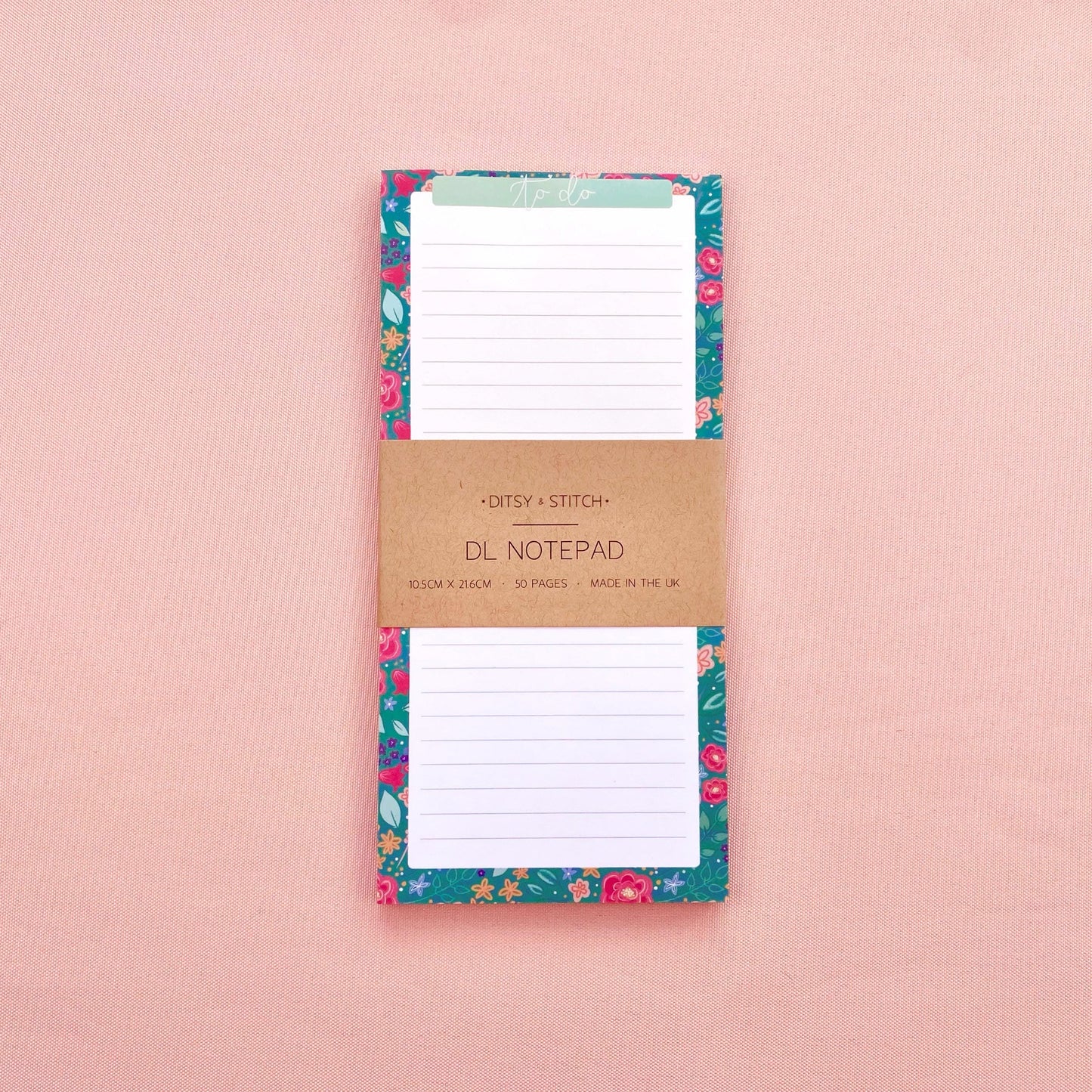 Floral notepad with a brown kraft paper cover on a pink background
