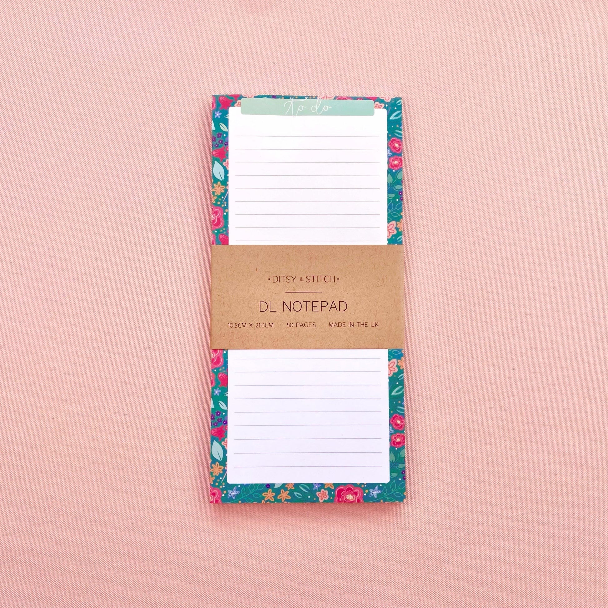 Floral notepad with a brown kraft paper cover on a pink background