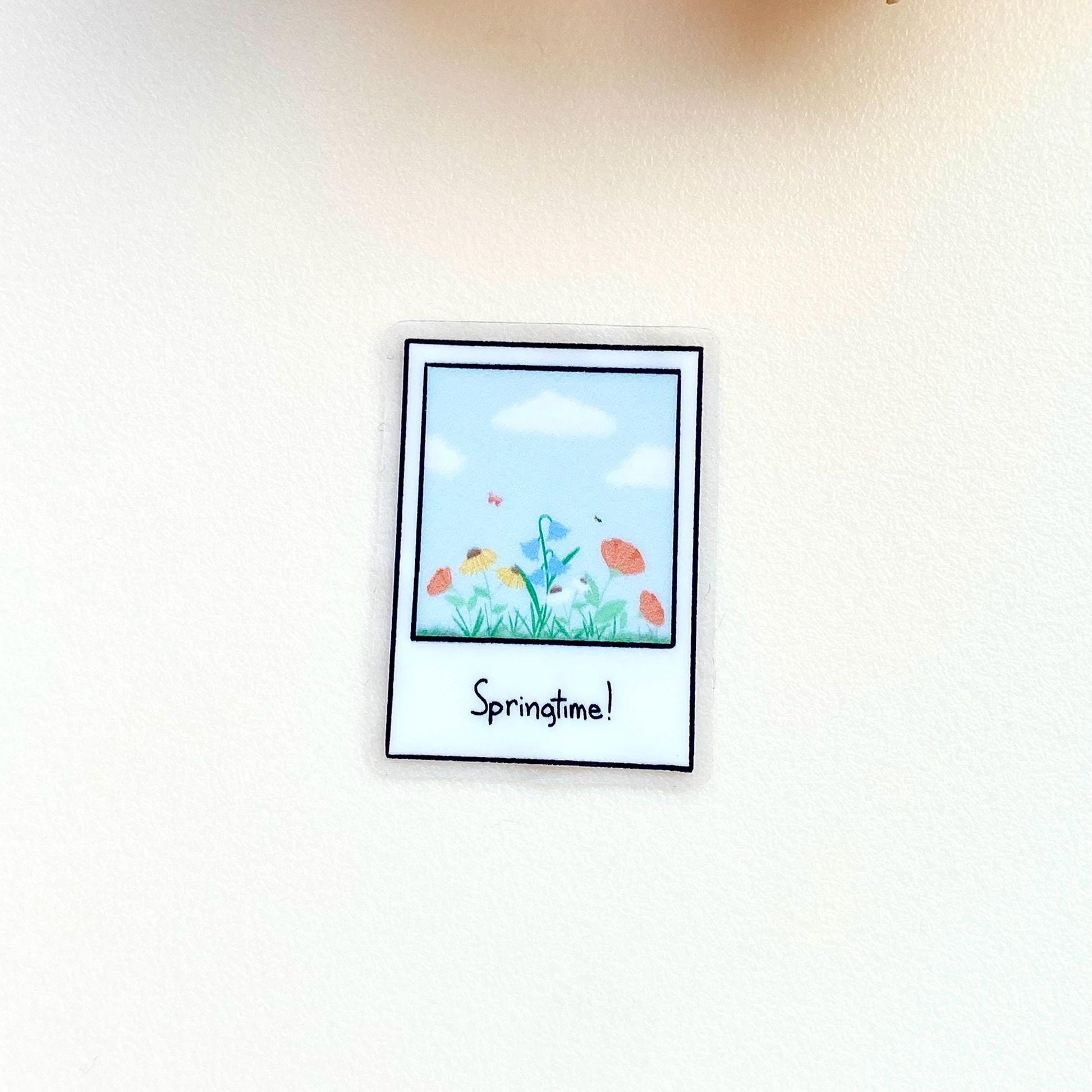 Clear sticker with a polaroid design showing a spring scene with the text 'Springtime!'