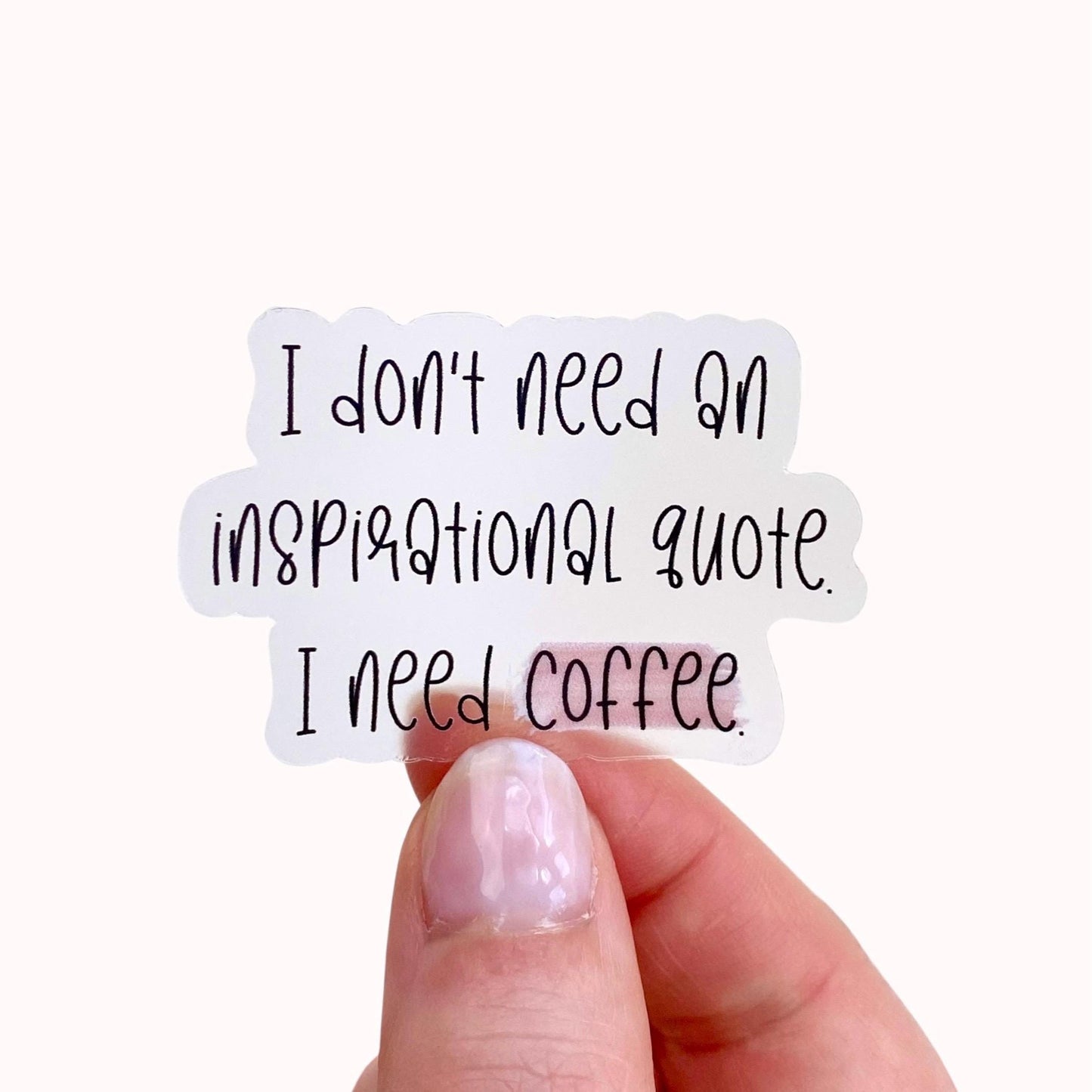 Hand holding a sticker with the text 'I don't need an inspirational quote, I need coffee.'