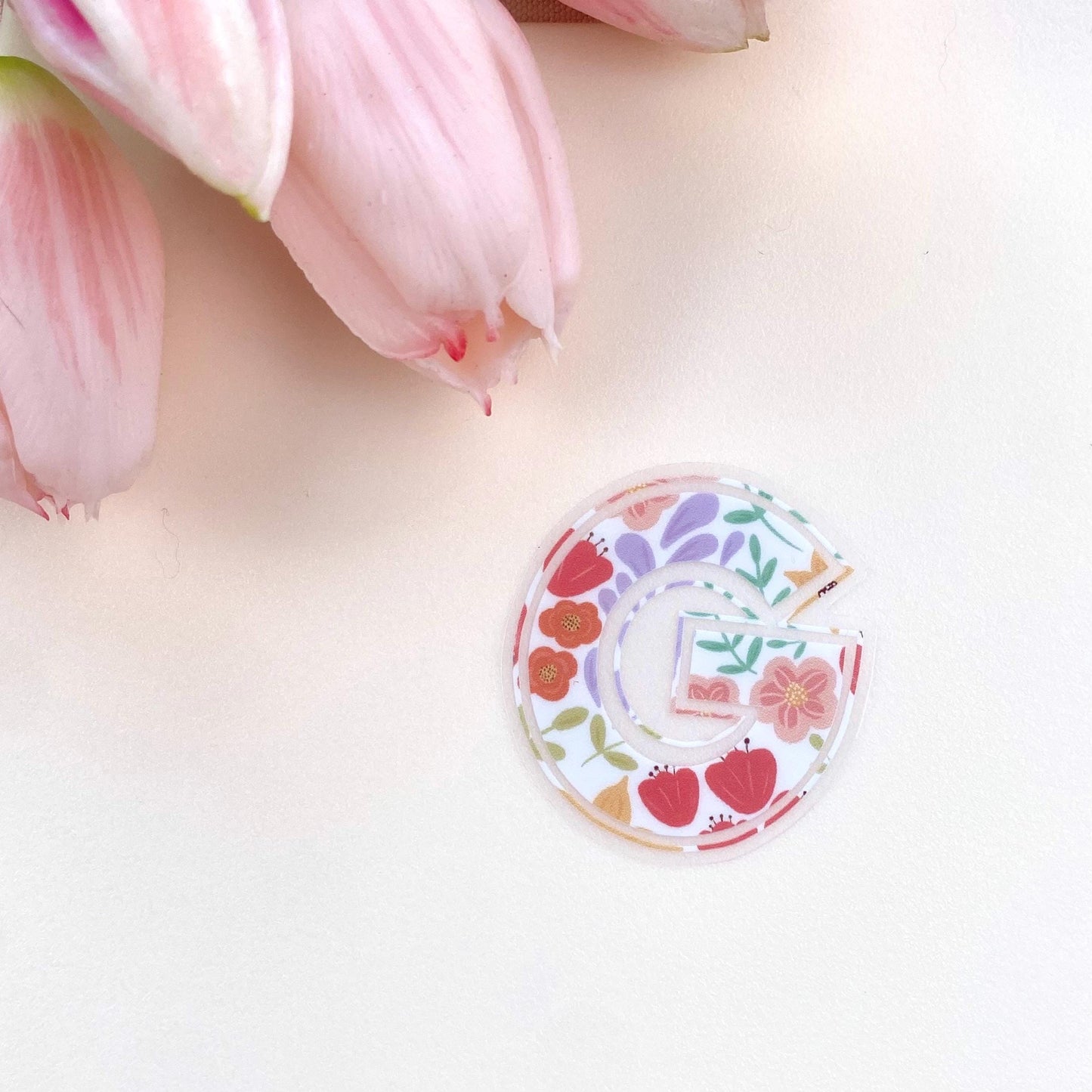 Decorative letter 'G' sticker with floral design on a white background with pink tulips