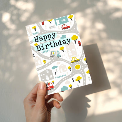 Hand holding a birthday card with road and vehicle pattern