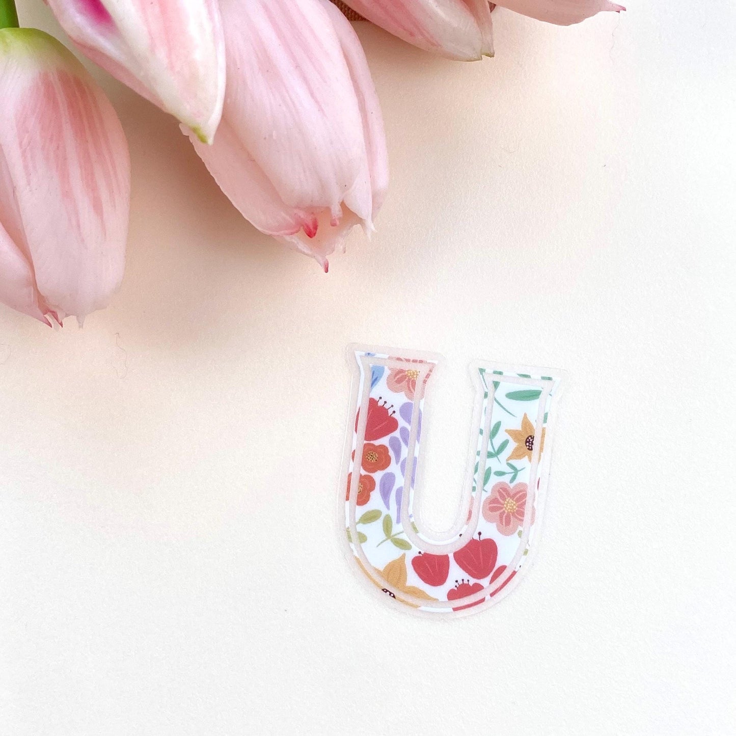Floral-patterned letter 'U' sticker on a light background with pink tulips