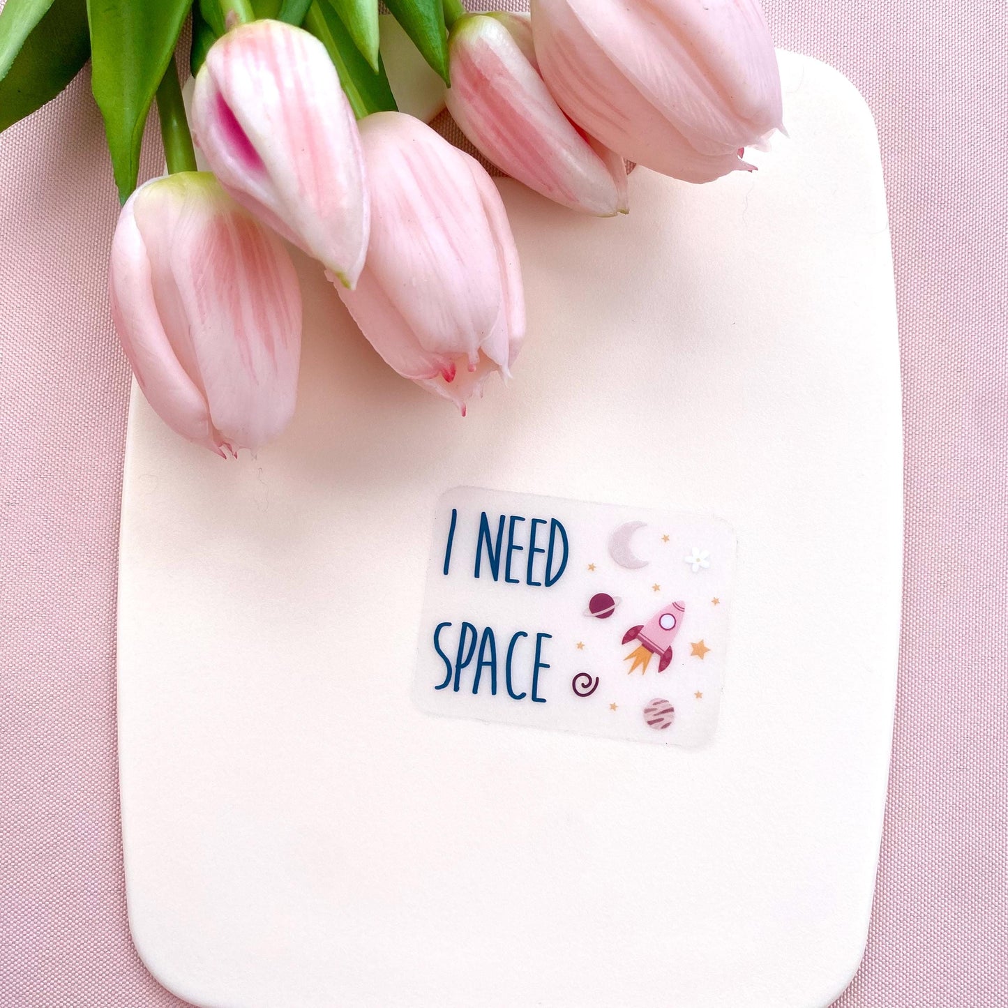 Transparent sticker with 'I NEED SPACE' text and space illustrations against a white background with pink tulips.
