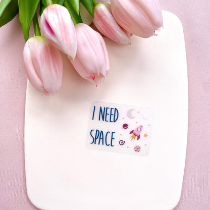 Transparent sticker with 'I NEED SPACE' text and space illustrations against a white background with pink tulips.
