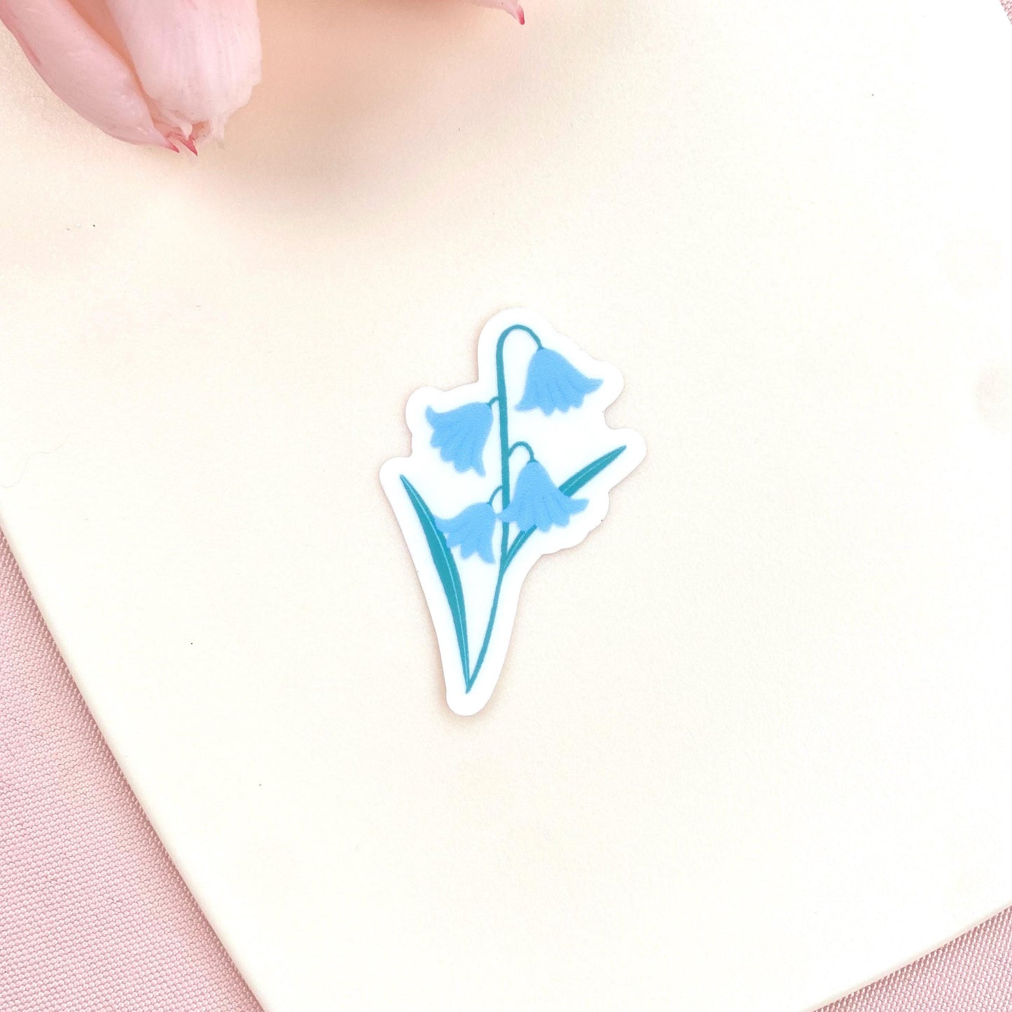 Blue flower-shaped sticker on a light pink background