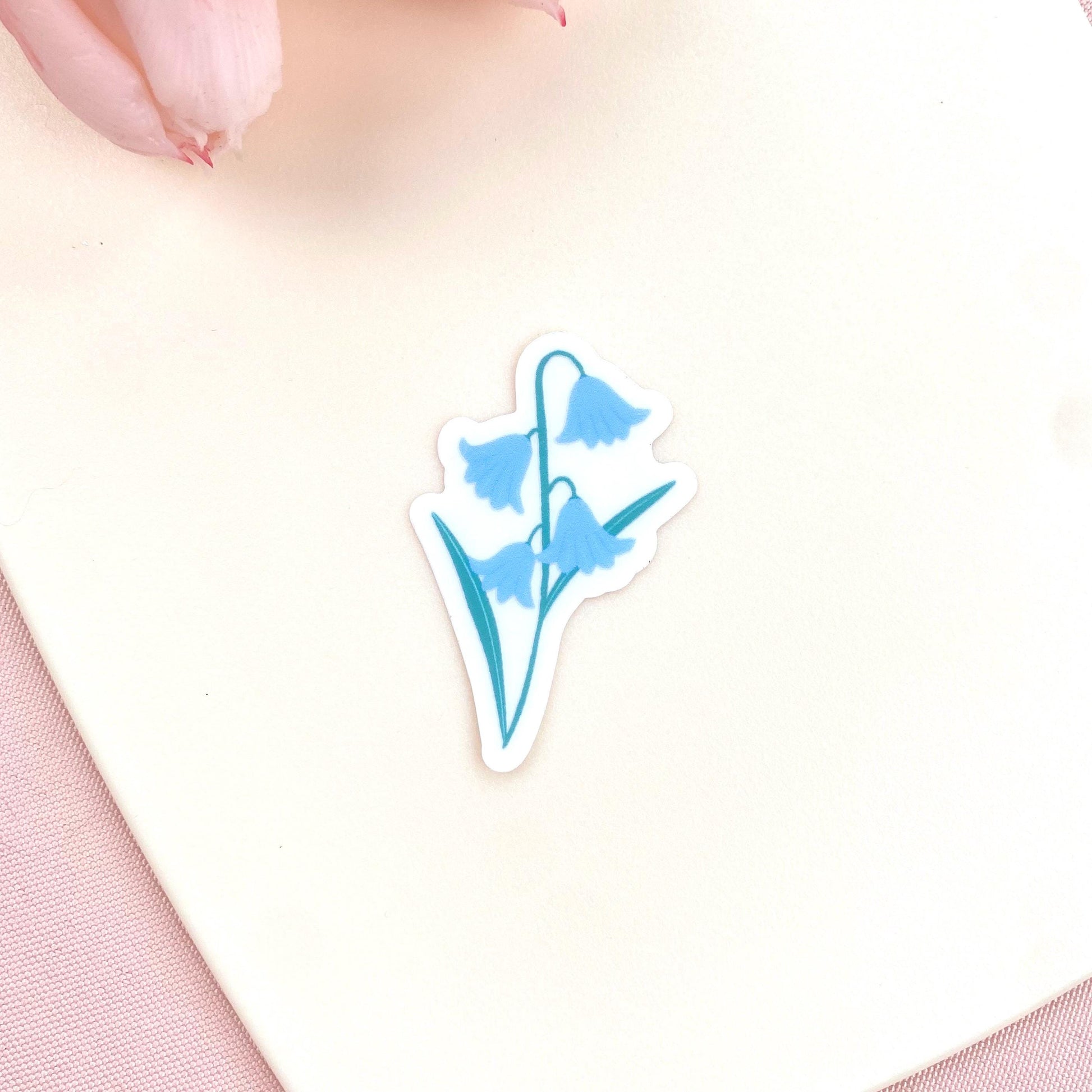 Blue flower-shaped sticker on a light pink background