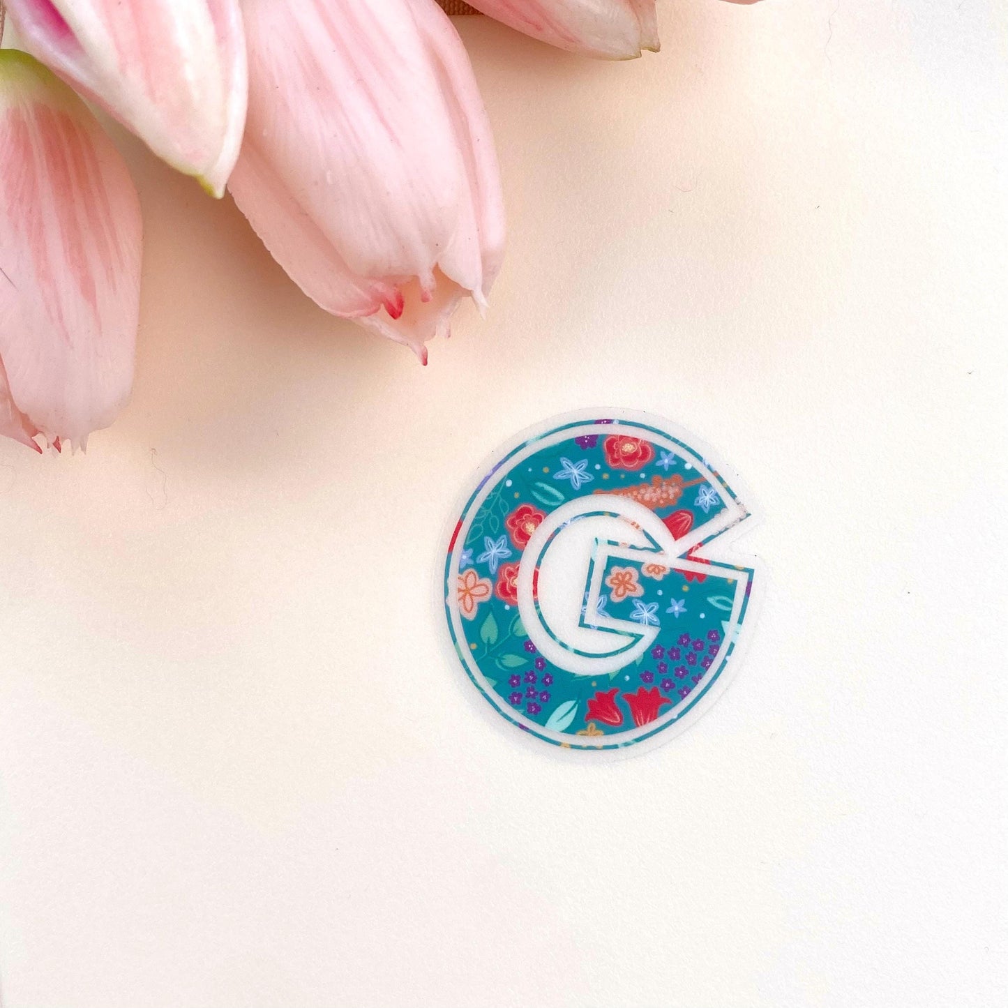 Decorative letter 'G' sticker with floral design on a light background