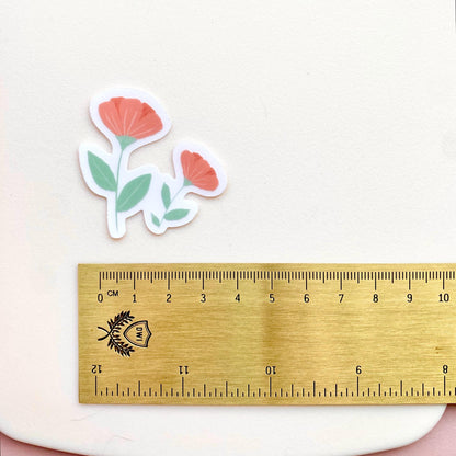 Pink flowers sticker against a cream background with a gold ruler for scale.