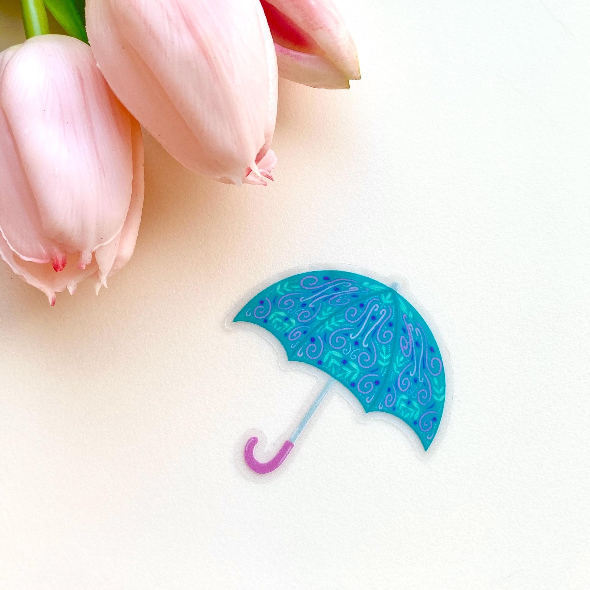 Blue decorative umbrella with pink handle on a white background with pink tulips.