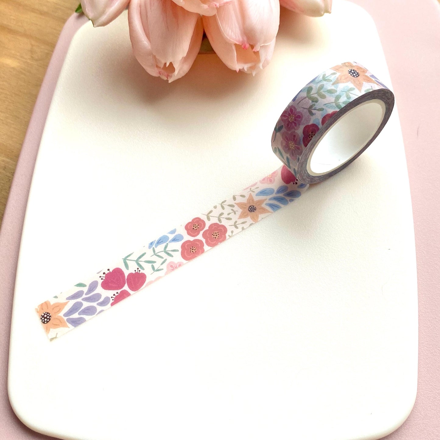 Floral-patterned tape on a white surface with pink flowers in the background