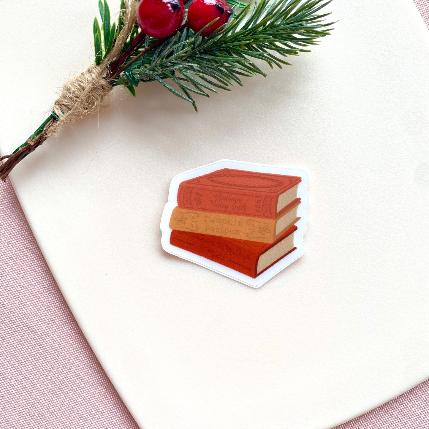 Stack of autumn books sticker on a white surface with a branch and berries