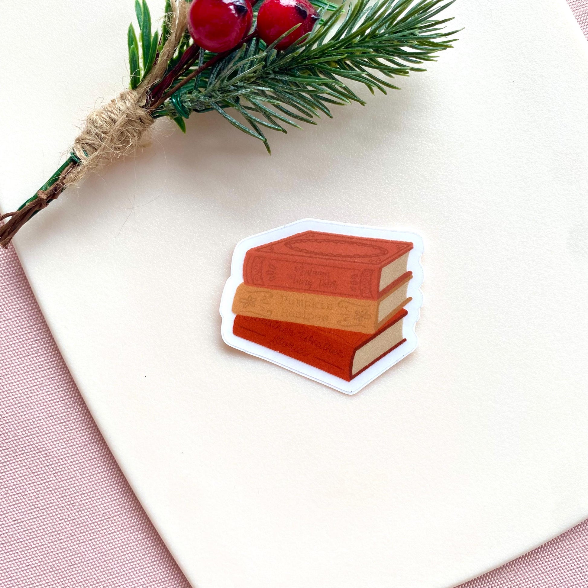 Stack of autumn books sticker on a white surface with a branch and berries