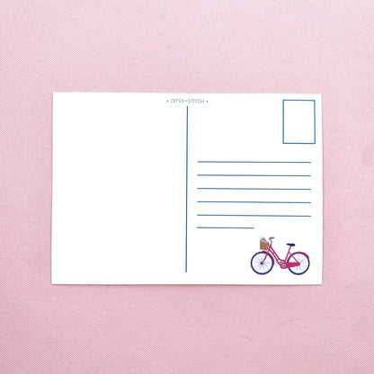 Postcard with a bicycle illustration on a pink textured background