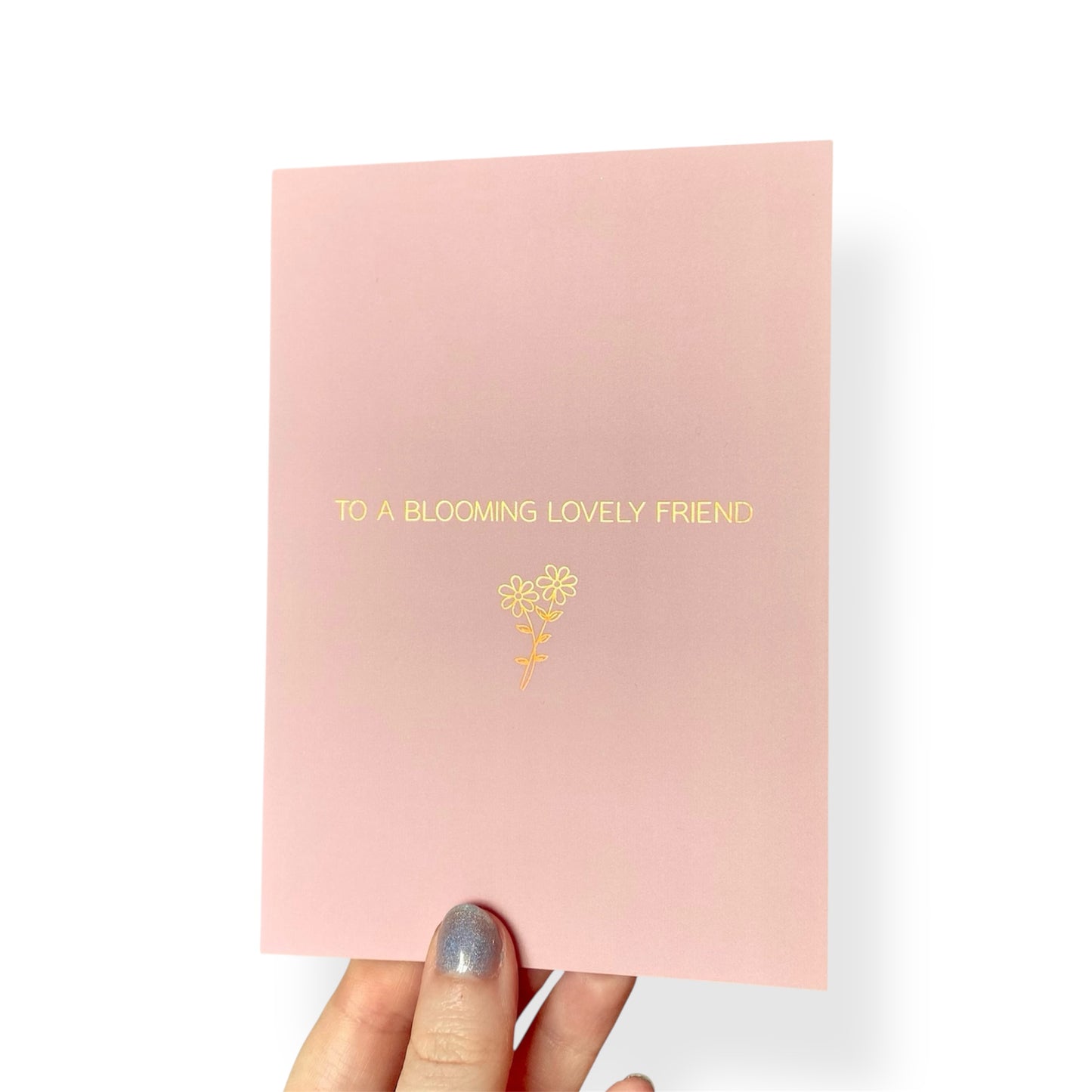 A simple pink card with ‘For a blooming lovely friend’ in rose gold text and a foiled flower outline.