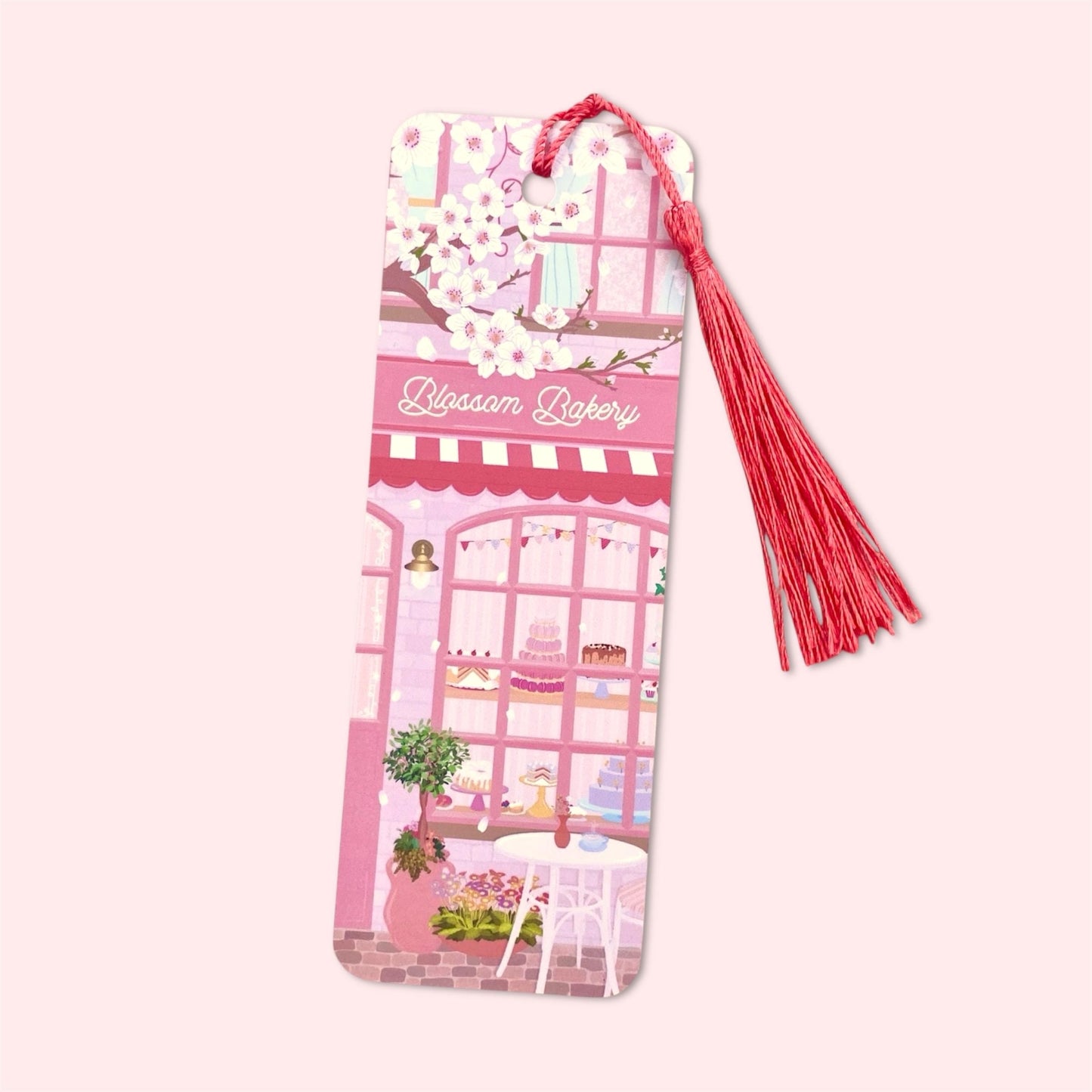 Bookmark with a pink bakery design and bright pink tassel on a light pink background