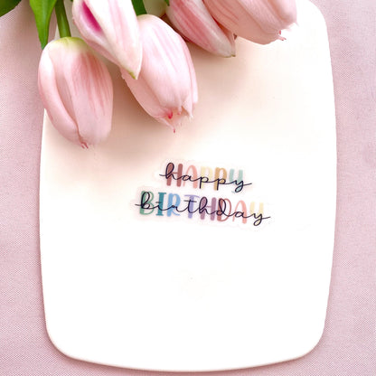 Colourful transparent 'Happy Birthday' sticker on a white background with pink tulips