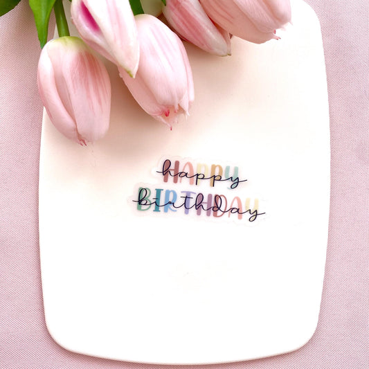 Colourful transparent 'Happy Birthday' sticker on a white background with pink tulips