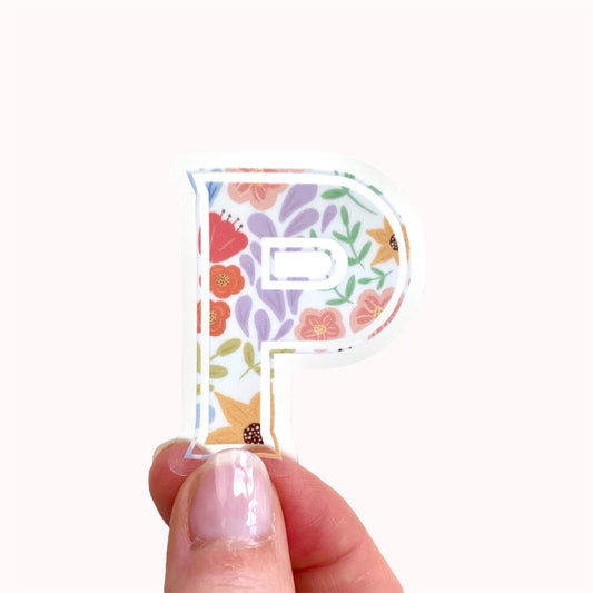 Floral letter 'P' sticker held between fingers on a white background