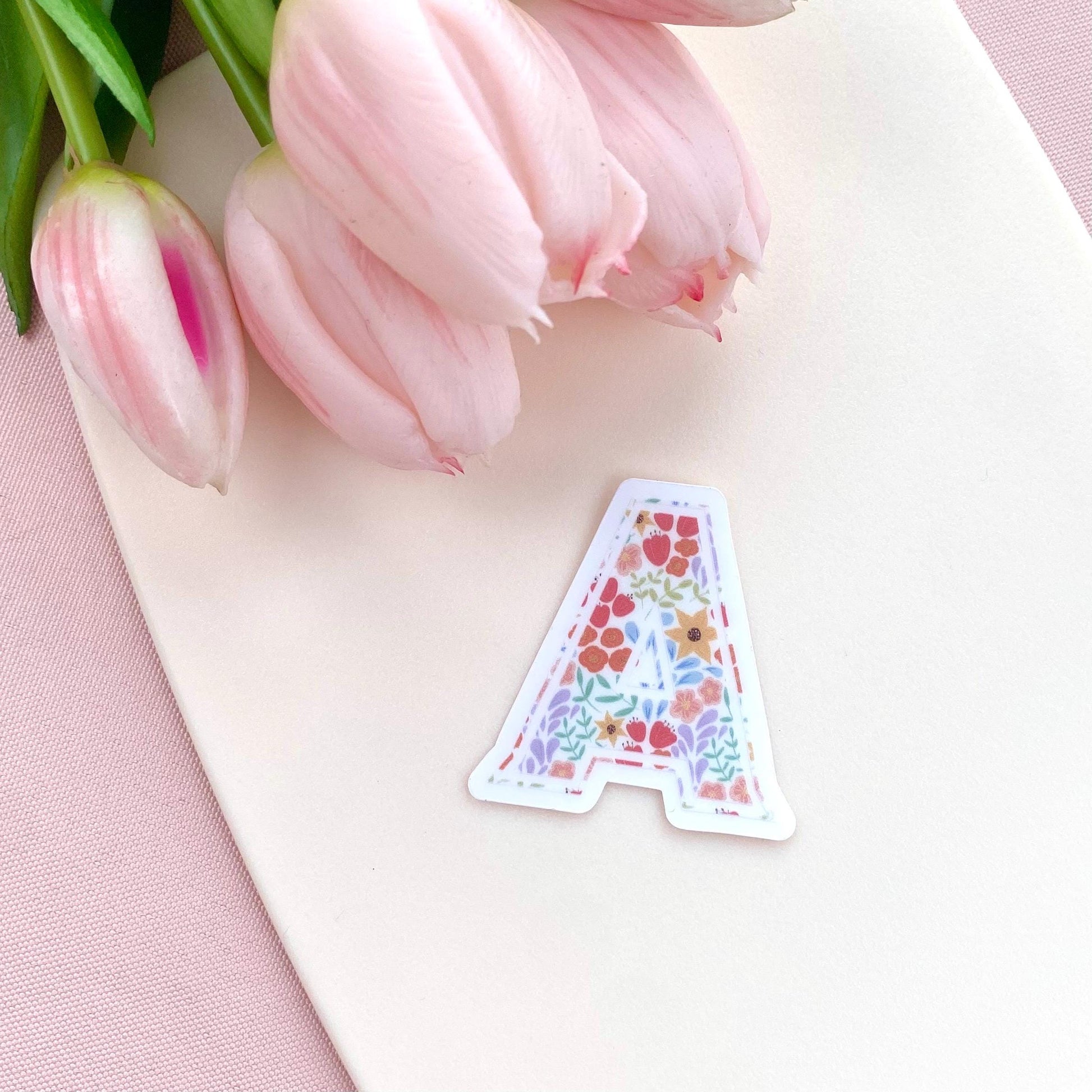 Decorative letter 'A' sticker with floral pattern on a white background with pink tulips.