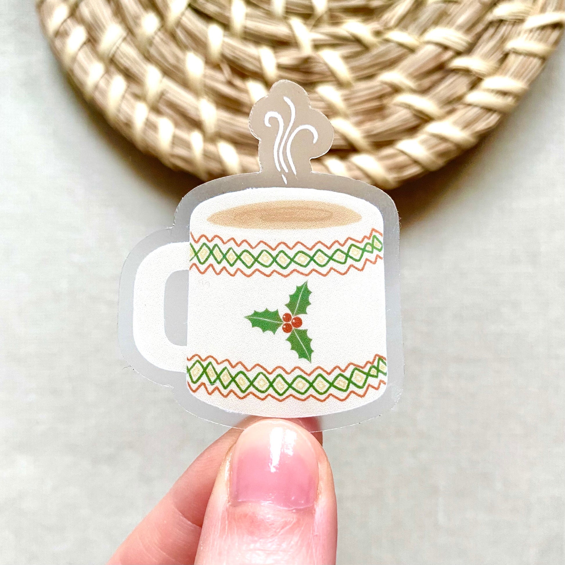 Decorative Christmas mug sticker held by a hand with a woven mat in the background