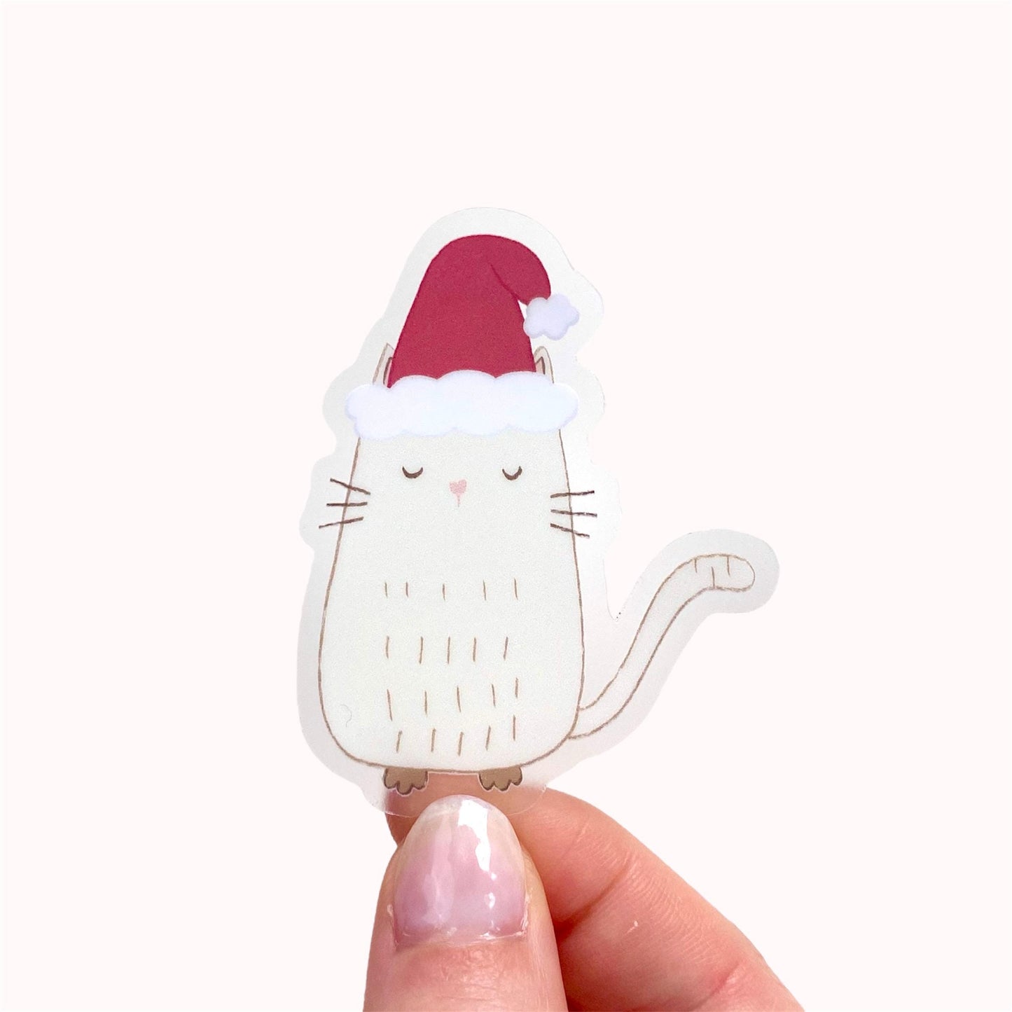 Sticker of a cat wearing a Santa hat held by a hand on a white background