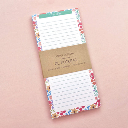 Floral bordered and lined slim notepad on a pink background