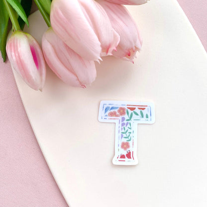 Floral letter 'T' sticker on a pink surface with pink tulips