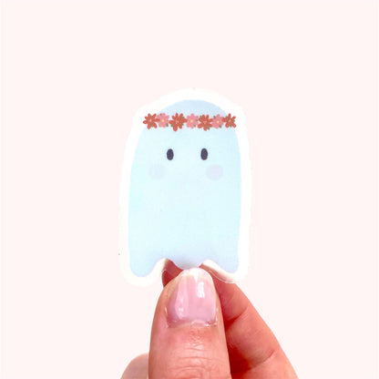 Ghost sticker with a floral headband held by a hand on a white background