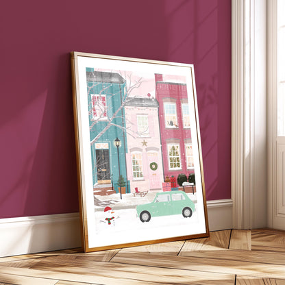 Framed artwork of a snowy street scene with buildings and a car on a purple wall.