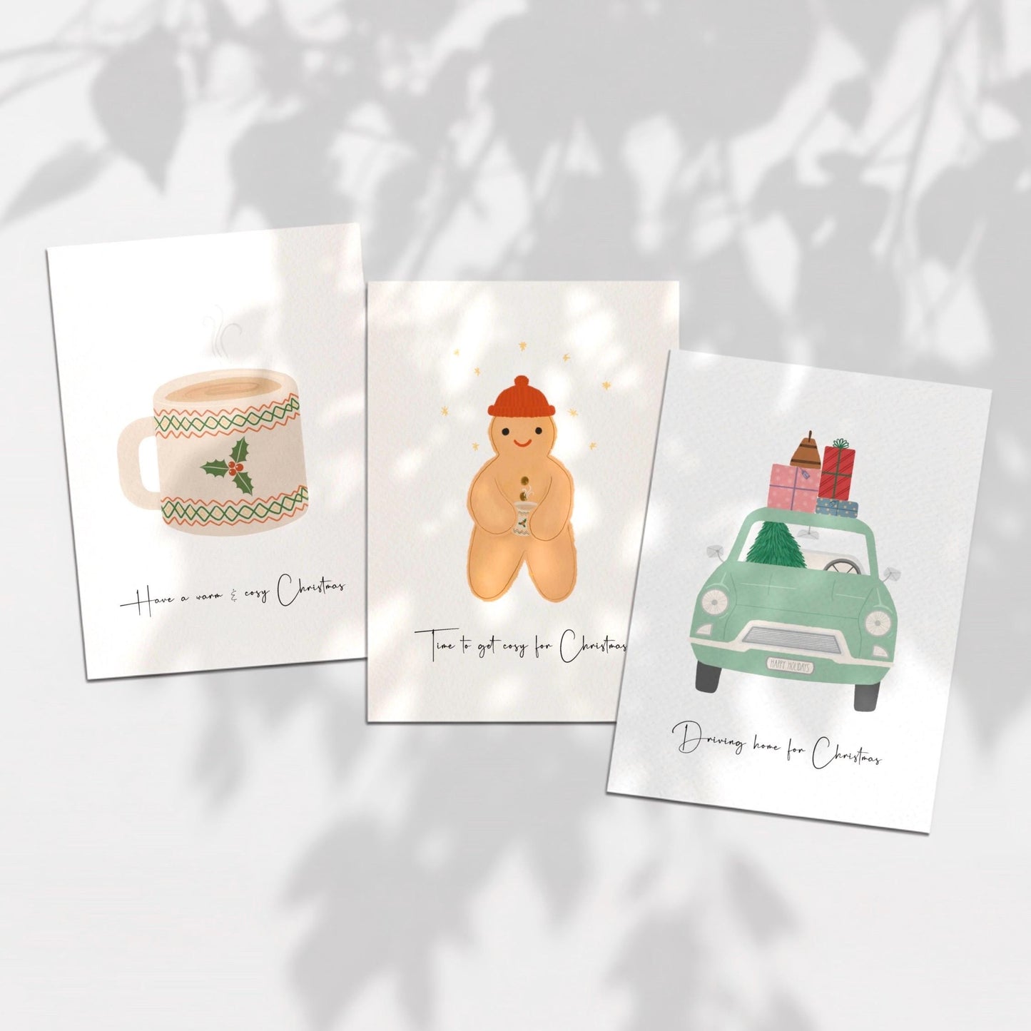 Three Christmas-themed cards on a light background with leaf shadows.