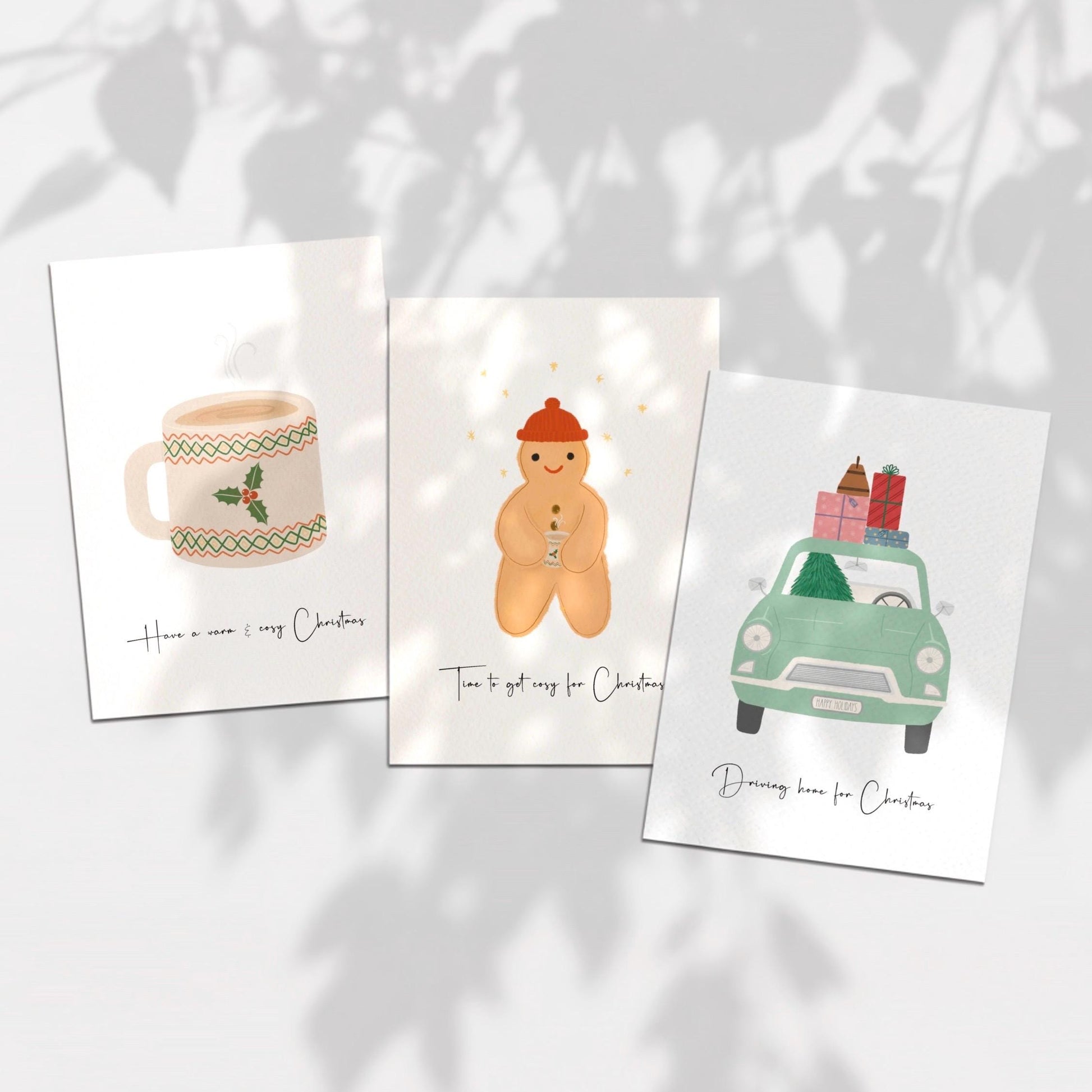 Three Christmas-themed cards on a light background with leaf shadows.
