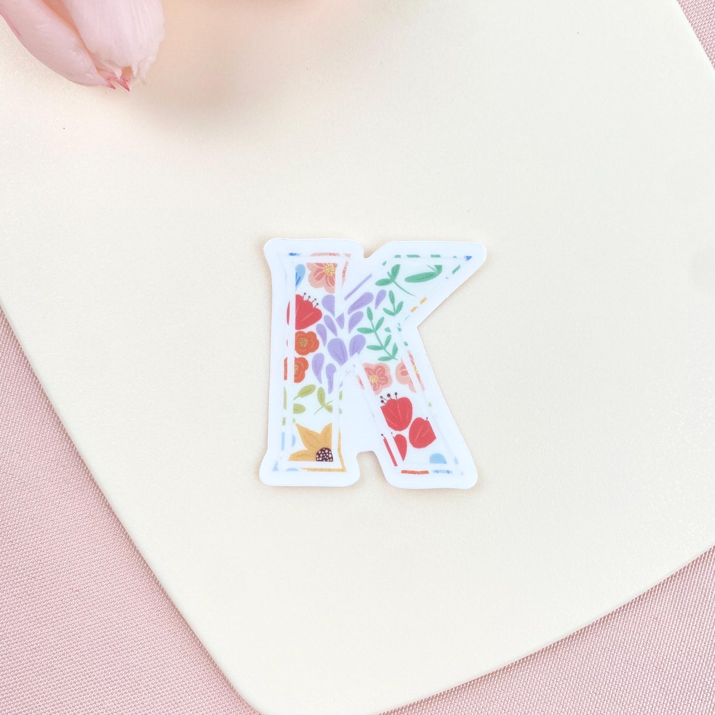 Colorful letter 'K' sticker on a light pink background