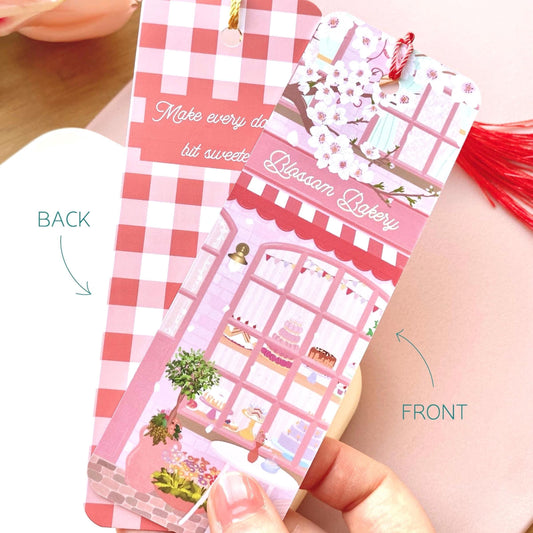 Pink and white bakery-themed bookmark held by a hand, showing front and back views.