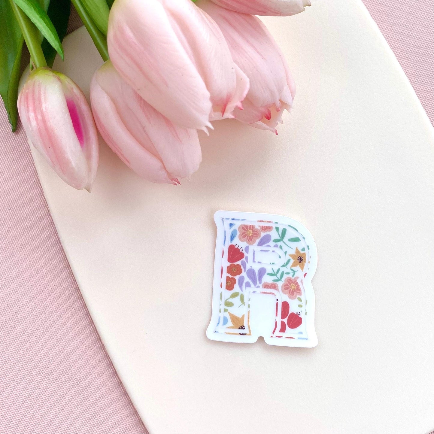 Decorative letter 'R' sticker with floral design on a white background