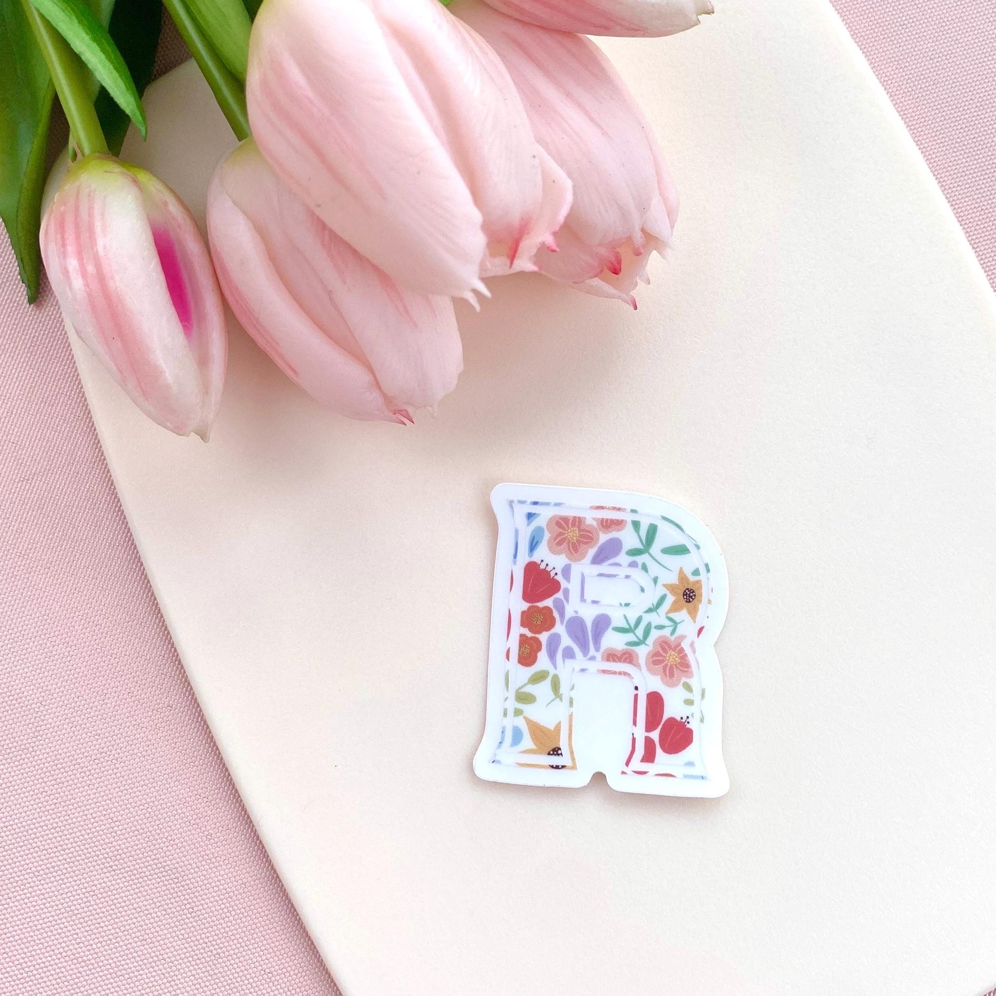 Decorative letter 'R' sticker with floral design on a white background