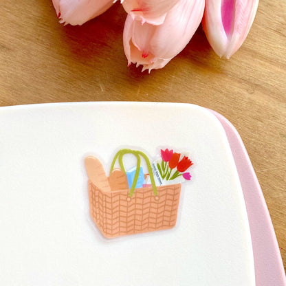 Sticker of a picnic basket with flowers on a white surface with pink border