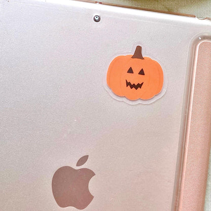 Orange jack-o-lantern pumpkin sticker stuck to the back of a pink ipad.