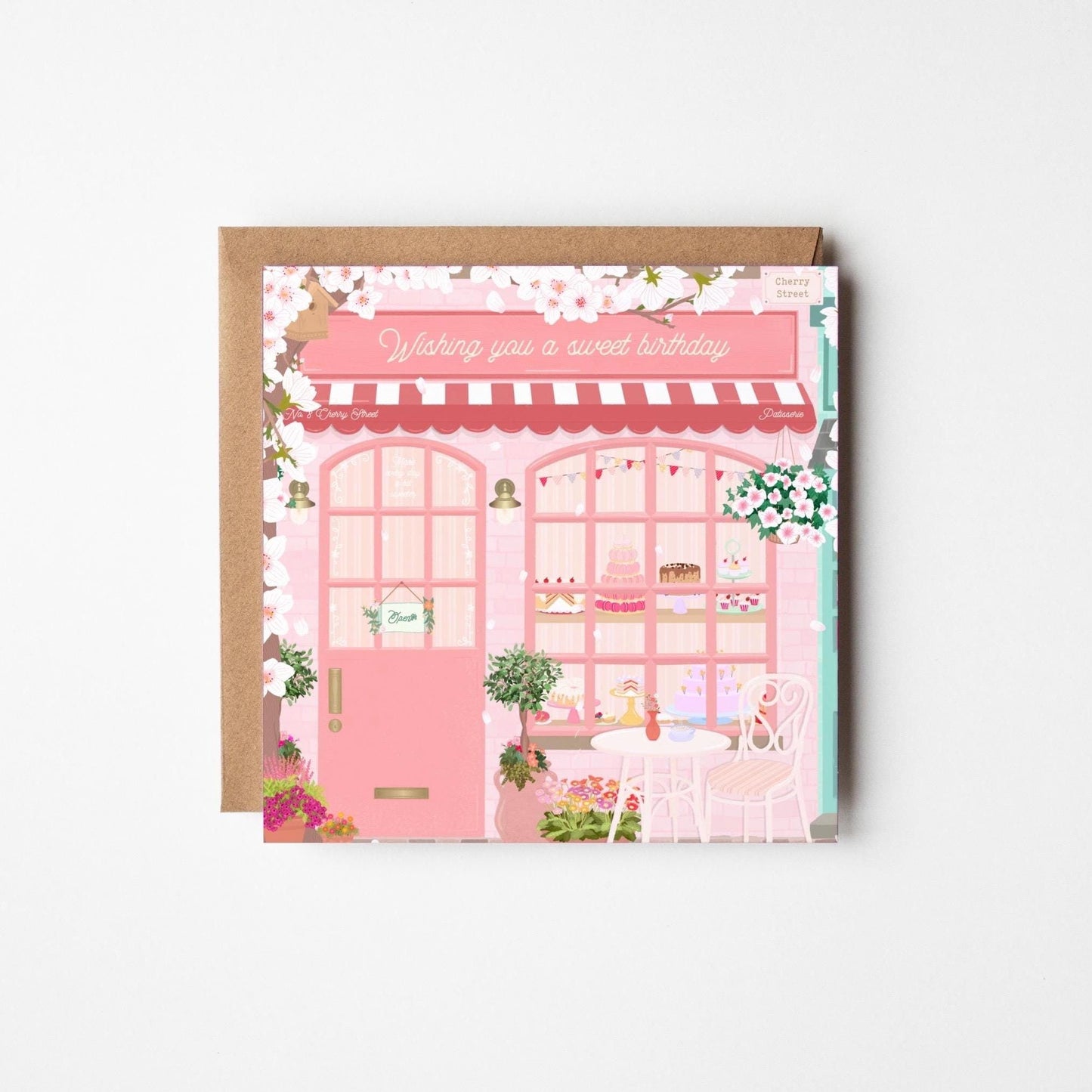 Card with a pink bakery illustration and 'Wishing you a sweet birthday' text on a brown envelope.