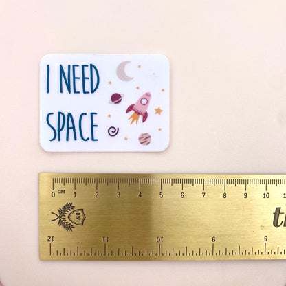 Sticker with 'I Need Space' text and space-themed illustrations next to a ruler for size reference.